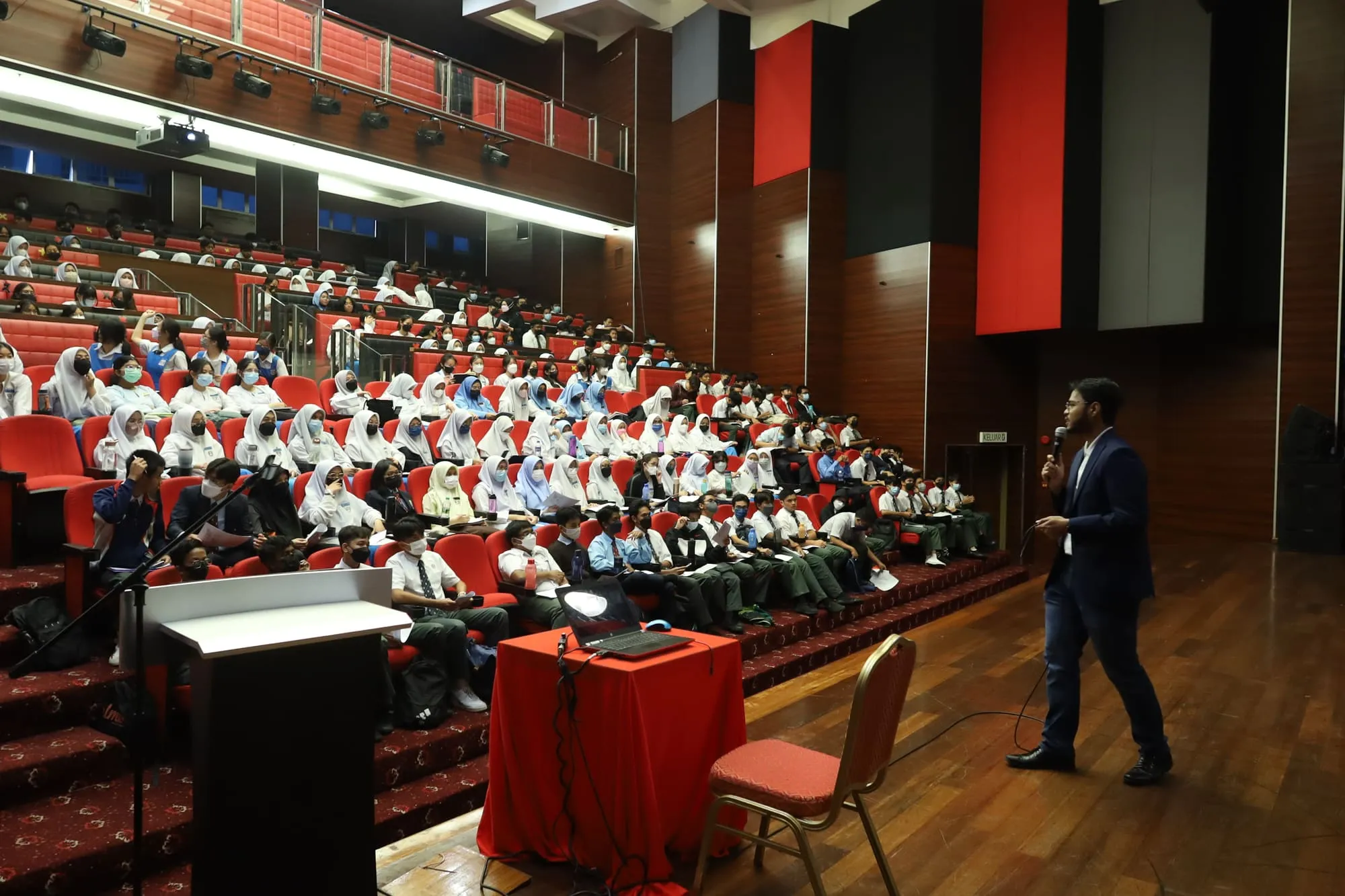 Hundreds of secondary school students fill a university auditorium as Mifzal Salihin walks the stage